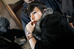 The inticate wrist-and-hand jewellery, coupled with the contrasting fur trim on the hood, suggest a wealthy Highborn.