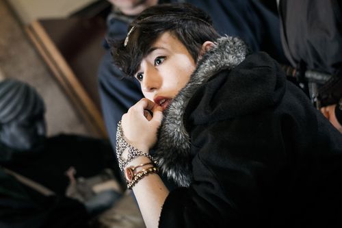 The inticate wrist-and-hand jewellery, coupled with the contrasting fur trim on the hood, suggest a wealthy Highborn.