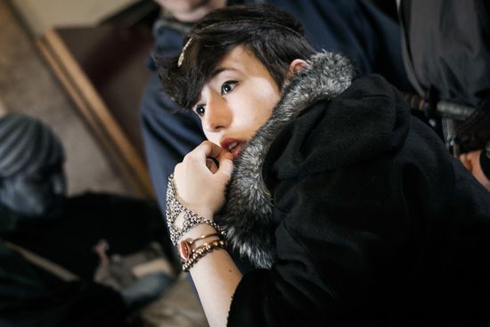 The inticate wrist-and-hand jewellery, coupled with the contrasting fur trim on the hood, suggest a wealthy Highborn.