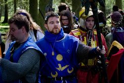 Tancred wears a surcote bearing his personal heraldry over a shirt of thick, heavy chain.
