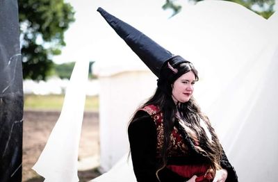 An extravagant conical hat with trailing fabric.